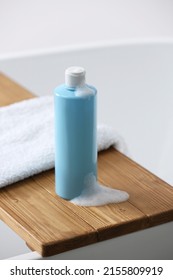 Bottle Of Bubble Bath With Foam And Towel On Tub In Bathroom