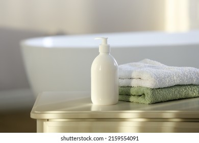 Bottle Of Bubble Bath And Towels On White Table In Bathroom, Space For Text