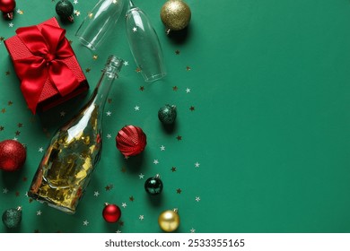 Bottle of champagne, glasses, gift box and Christmas balls on green background - Powered by Shutterstock