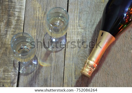 a bottle of champagne and glasses on the background of a Christmas tree decorated with balls and New Year's lights. happy christmas concept. Ribbon, baubles and wine against Christmas lights