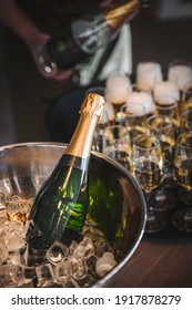 bottle of champagne in ice and person pouring glasses in the background