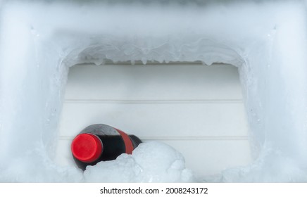 A bottle of cola soft drinks with ice cubes on freezing compartment of refrigerator, copy space for text.