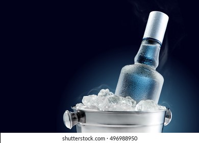 Botella de vodka frío en cubo de hielo sobre fondo oscuro