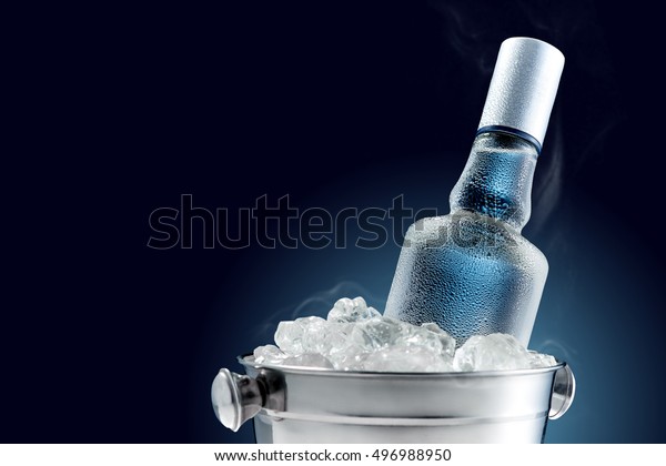 Bottle\
of cold vodka in bucket of ice on dark\
background