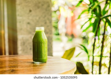 Bottle with cold-pressed green juice, nature background, sunny morning. Healthy eating, detoxing, juicing, fasting, body cleancing concept