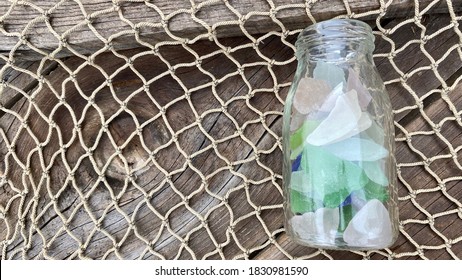 Bottle Of Colorful Sea Glass On Fishing Net. Top View Photograph.  