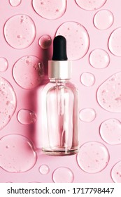 Bottle of cosmetic liquid transparent gel with bubbles on pink background. Flat lay style.