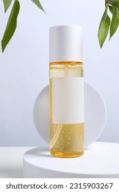 Bottle of cosmetic product and leaves on white wooden table - Shutterstock ID 2315903267