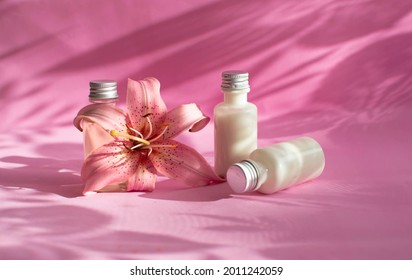 A Bottle Of Cream, Lotion, Mousse, Cleanser, Shampoo For Skin And Hair Care. White Plastic Packaging In A Row On A Bright Pink Background Decorated With Shadows Of Flowers. Layout Of Salon Products.