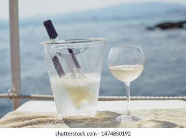 Bottle Of Crisp, Light Rose Wine In Ice Bucket And Wineglass Filled Halfway. Both Standing On Light Surface With The Beautiful Mediterranean Sea In The Background. Cannes, France -Image 