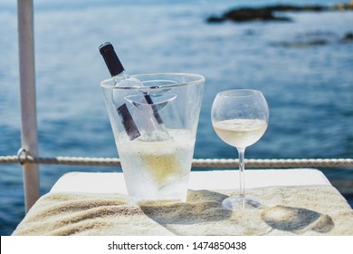 Bottle Of Crisp, Light Rose Wine In Ice Bucket And Wineglass Filled Halfway. Both Standing On Light Surface With The Beautiful Mediterranean Sea In The Background. Cannes, France -Image 