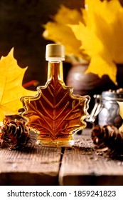 A bottle of delicious maple syrup with maple leaves on wooden forest background