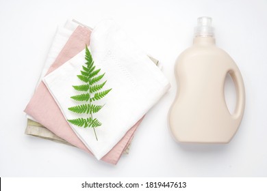 Bottle With Eco Detergent And Linen Clean Napkins With Green Fern Branch On White Background. Eco-friendly Laundry Concept