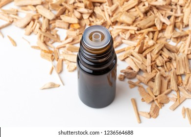 A bottle of essential oil with cedar wood chips