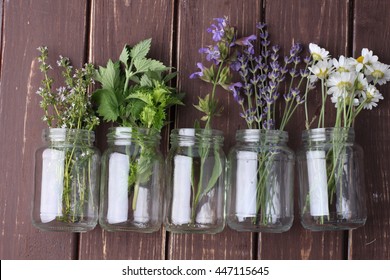 Bottle Of Essential Oil With Herbs Oregano, Sage, Camomile, Lavander, Parsley, Thyme And Mint Set Up On Old Wooden Background.