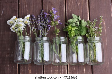 Bottle Of Essential Oil With Herbs Oregano, Sage, Camomile, Lavander, Parsley, Thyme And Mint Set Up On Old Wooden Background.