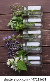 Bottle Of Essential Oil With Herbs Oregano, Sage, Camomile, Lavander, Parsley, Thyme And Mint Set Up On Old Wooden Background.