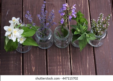 Bottle Of Essential Oil With Herbs Oregano, Sage, Camomile, Lavander, Parsley, Thyme And Mint Set Up On Old Wooden Background.