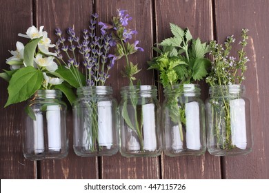 Bottle Of Essential Oil With Herbs Oregano, Sage, Camomile, Lavander, Parsley, Thyme And Mint Set Up On Old Wooden Background.