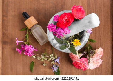 Bottle Of Essential Oil, Marble Mortar And Different Flowers On Wooden Board, Top View