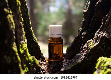 Bottle Of Essential Oil On A Blurred Background Of Wood And Moss. Natural Or Alternative Medicine. Aromatherapy, Beauty Concept. Selective Focus.