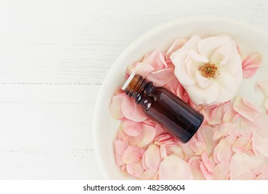 Bottle Of Essential Oil With Rose Pink Petals And Flower, On Clay Plate, Top View, Safe, Natural And Aromatic Skincare Ingredients.