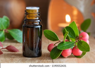 A Bottle Of Essential Oil With Wintergreen Leaves And Berries