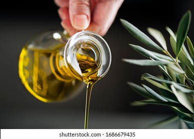 Bottle Of Extra Virgin Olive Oil Pouring On Dark Background. Healthy Food Concept.