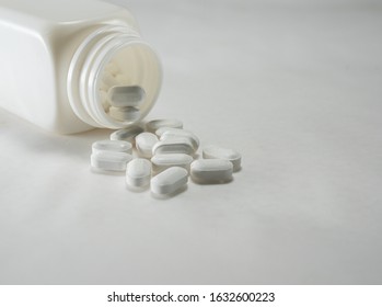 
A bottle of falling pills, a white pill. Analgesic Antibiotics for use in the treatment of necrosis Photos of close-up drugs on a white ground.