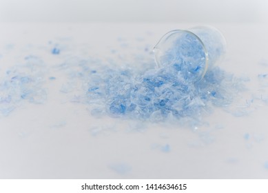 Bottle Flake,PET Bottle Flake,Plastic Bottle Crushed,Small Pieces Of Cut Blue Plastic Bottles In Beaker Glass.Chemical Concept