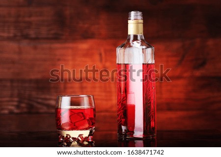 
bottle of flavored vodka with a glass on a wooden background