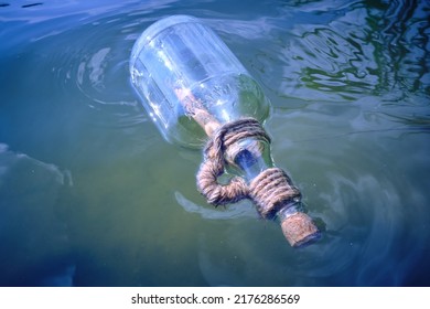 Bottle Floating On Water With A Rolled Letter Inside.Message Call For Help