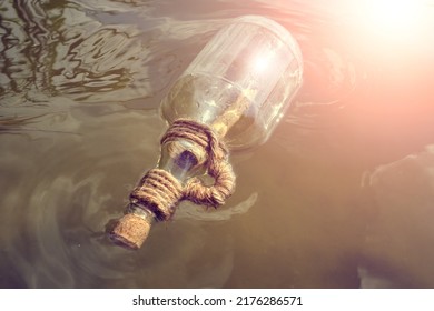 Bottle Floating On Water With A Rolled Letter Inside.Message Call For Help