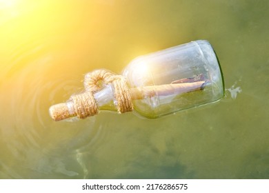 Bottle Floating On Water With A Rolled Letter Inside.Message Call For Help