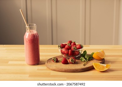 Bottle Of Fresh Homemade Strawberry Smoothie With Straw And Wooden Board With Pieces Of Juicy Orange And Mint Leaves