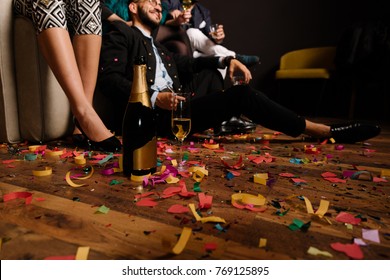 Bottle and glass of champagne on the confetti floor after party with people in background