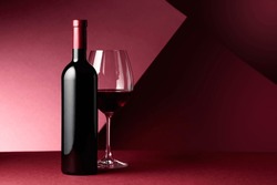 Bottle And Glass Of Red Wine On A Red Background. Copy Space.