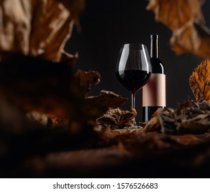 Bottle And Glass Of Red Wine On A Table With Dried Vine Leaves. Selective Focus. On A Bottle Empty Old Paper Label, Free Space For Your Text. Selective Focus.