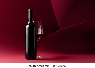 Bottle and glass of red wine on a red background. Copy space for your text. - Shutterstock ID 2044690802