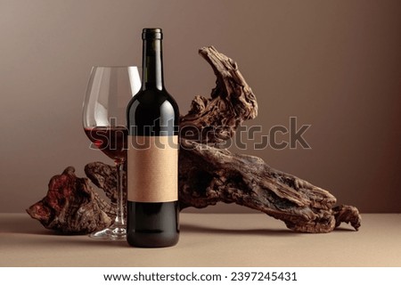 Bottle and glass of red wine. On a bottle old empty label. In the background old weathered snag. Frontal view with copy space.
