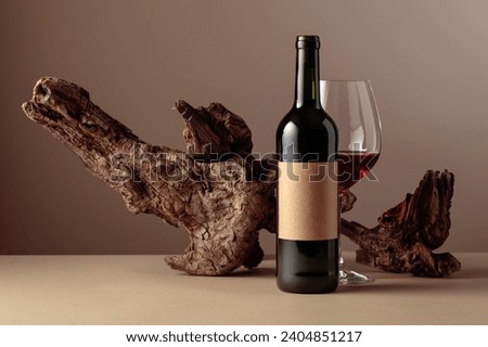 Bottle and glass of red wine. On a bottle old empty label. In the background old weathered snag. Frontal view with copy space.