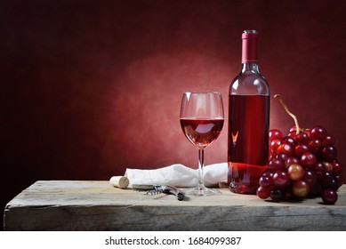 Bottle and glass of rose wine with bunch of grapes on an old wooden table. Space for text. - Powered by Shutterstock