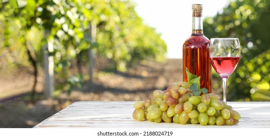 Bottle and glass of sweet wine with ripe grapes on table in vineyard - Shutterstock ID 2188024719