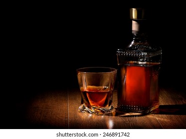 Bottle and glass of whiskey on a wooden table