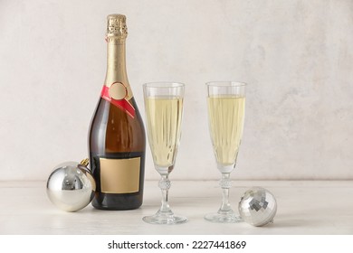 Bottle, glasses of champagne and Christmas balls on light wooden table - Powered by Shutterstock