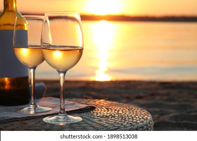 Bottle and glasses of delicious wine on riverside at sunset - Powered by Shutterstock