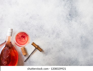 Bottle And Glasses Of Pink Rose Wine With Cork And Corkscrew Opener On Stone Kitchen Table Background. Top View.