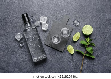 Bottle and glasses of vodka with lime on black background