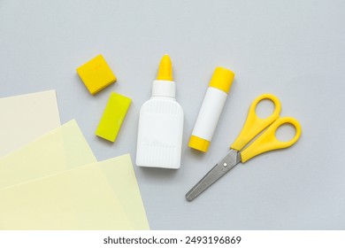 Bottle of glue, stick glue, scissors and eraser on grey background. Top view - Powered by Shutterstock