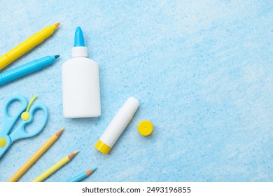 Bottle of glue, stick glue, scissors and felt-tip pen on blue grunge background. Top view - Powered by Shutterstock